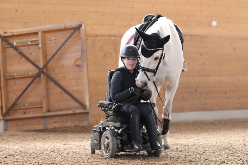 Ryttare sitter i rullstol bredvid sin häst 